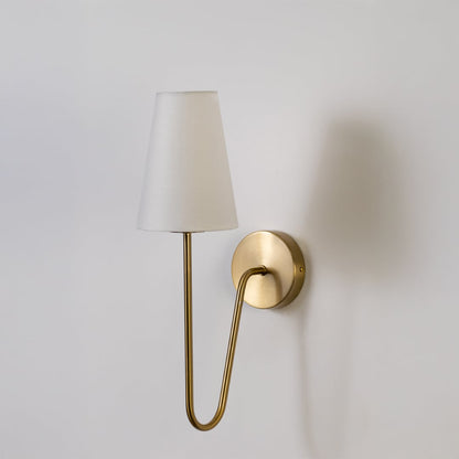Gold wall light with a tall white shade displayed on a plain white background showing its elegant shape.