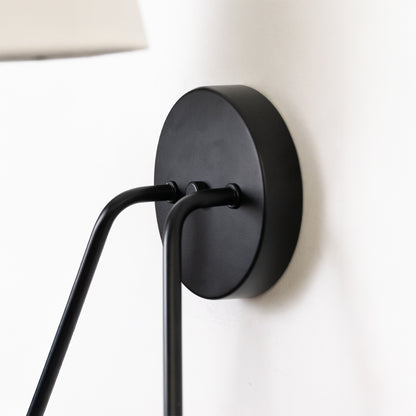 Contemporary wall light in black metal finish with adjustable arm for bedroom or living decor lighting white background.