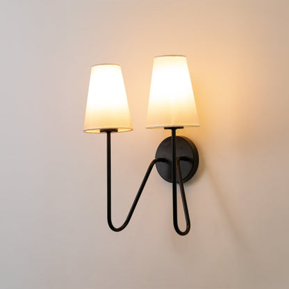 Black double wall light with two white shades glowing softly on a clean white background bringing a modern touch to home lighting decor.