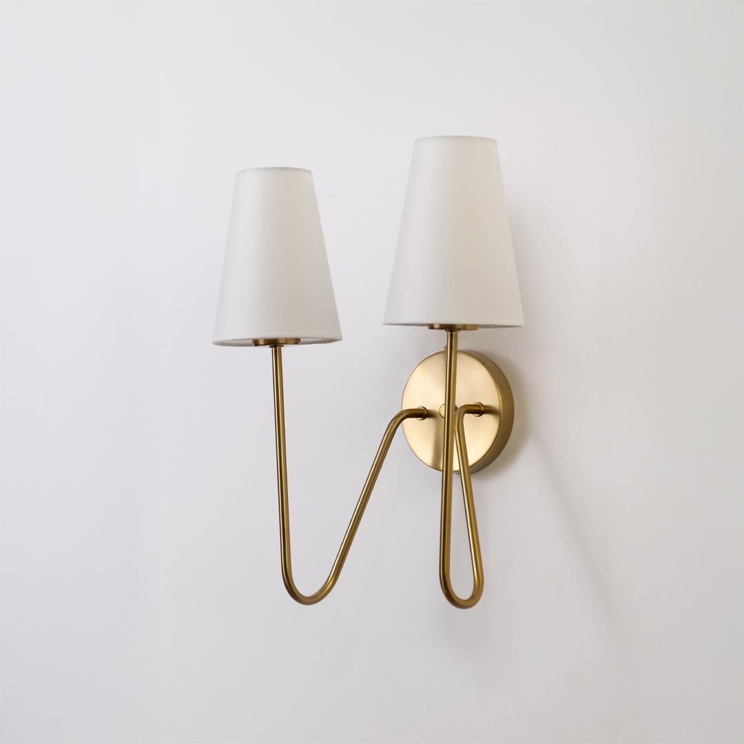 Stylish gold double wall light with twin white shades displayed on a white background perfect for bedroom hallway or living room lighting.