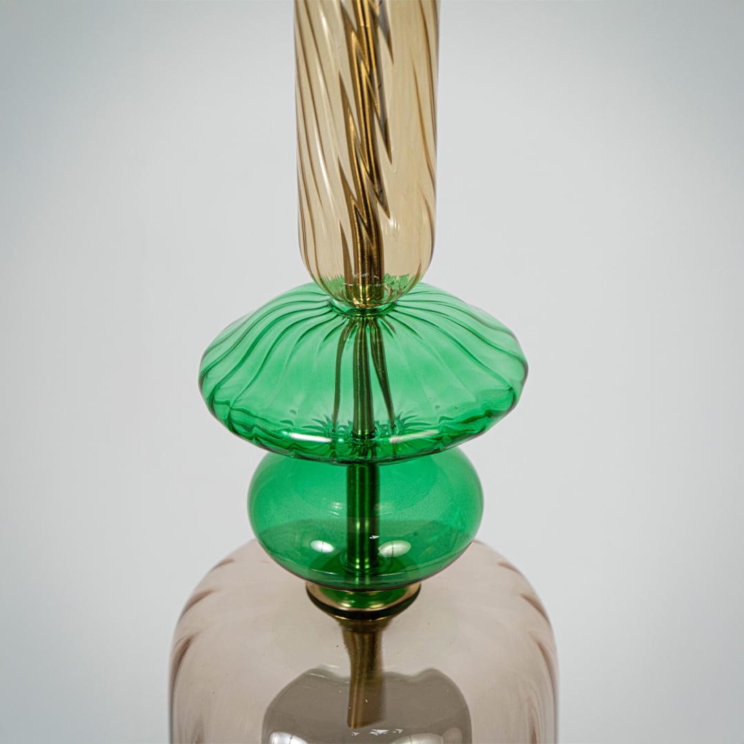 Closeup of clear glass pendant light with green details and twisted stem showcasing artisan craftsmanship.