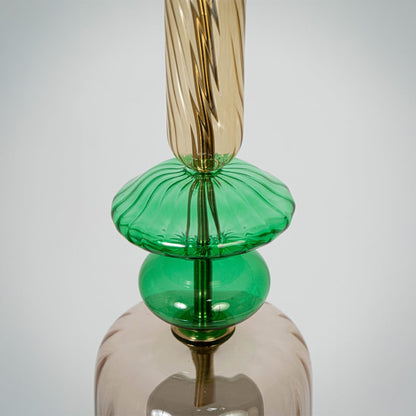 Closeup of clear glass pendant light with green details and twisted stem showcasing artisan craftsmanship.