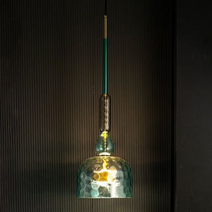 Rosetta teal glass pendant light glowing gently against a dark background highlighting its artistic glass texture.