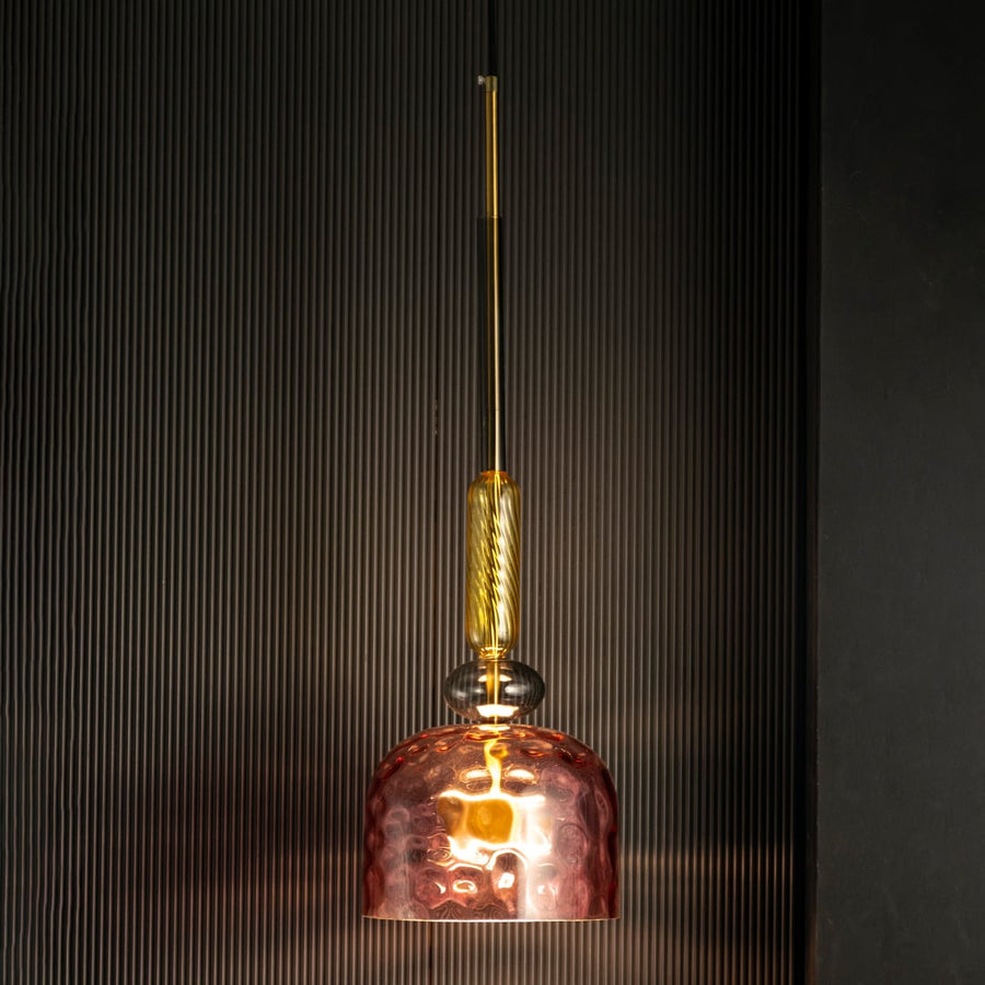 Rosetta pendant light on a black background showing elegant pink hammered glass shade and decorative golden yellow rod.