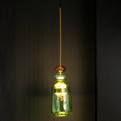 Rosetta green and pink glass pendant light glowing warmly against a dark background emphasizing its sculptural glass texture.