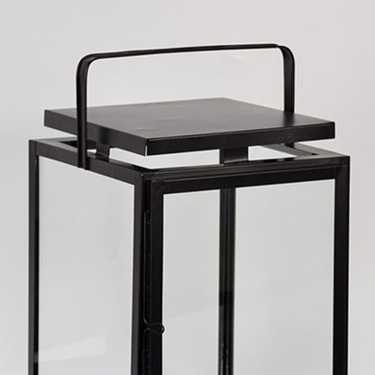Closeup of black metal lantern with flat top handle for modern indoor decor styling use.