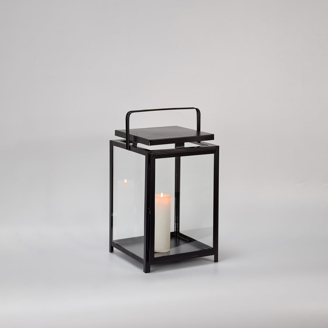 Black metal lantern with clear glass panels and candle holder for modern tabletop decor styling.