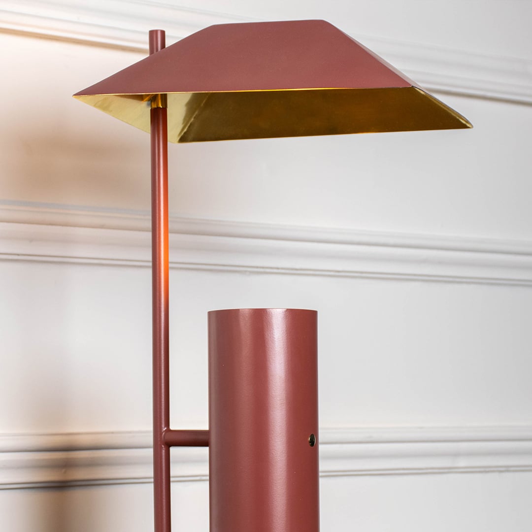 Closeup of terracotta brown metal table lamp showing geometric shade and cylindrical base for sleek contemporary decor.