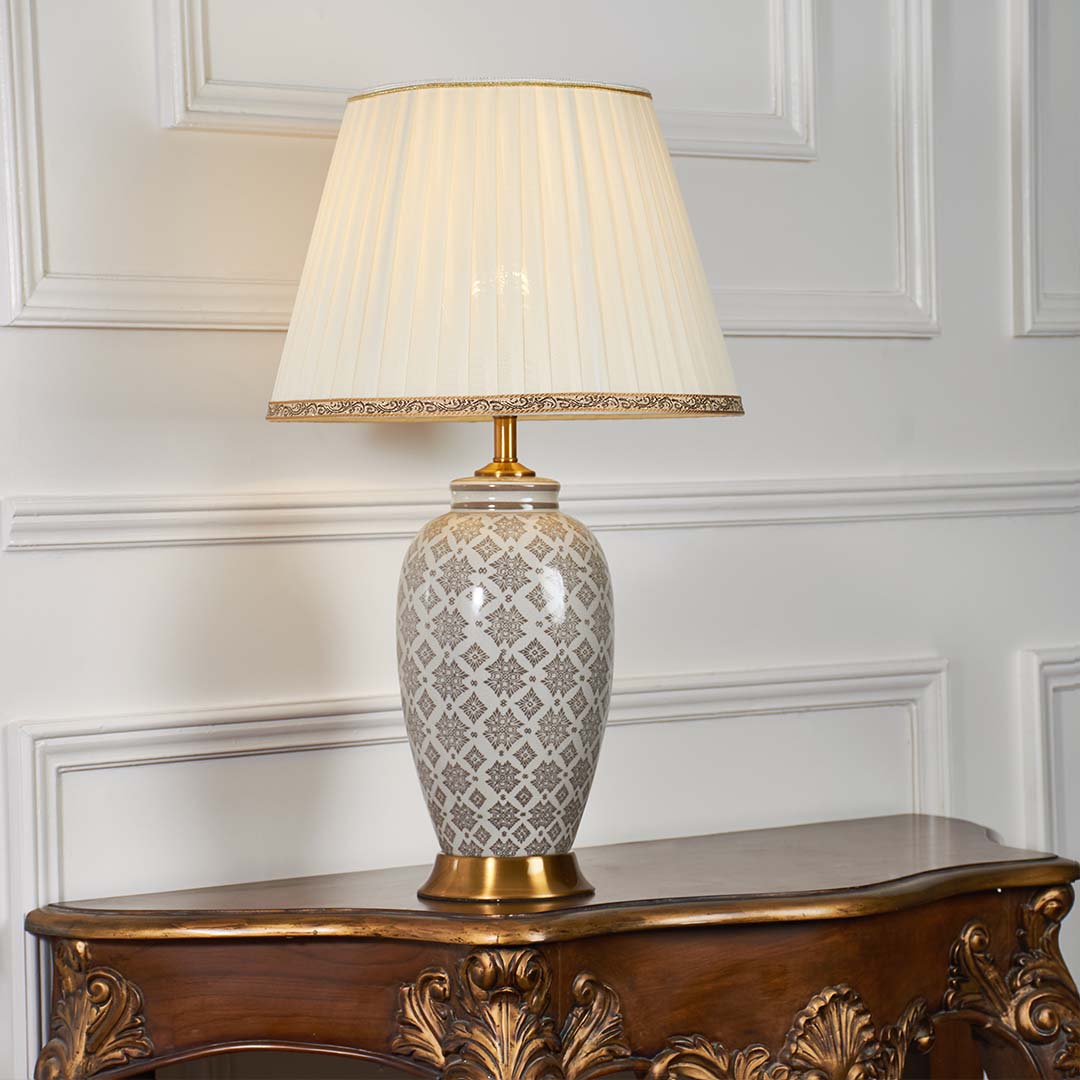 Grey patterned ceramic table lamp with pleated fabric shade creating warm ambient lighting and timeless decorative appeal.