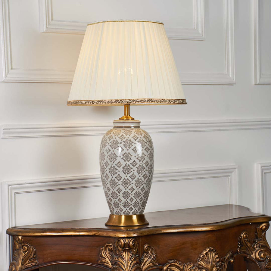 Grey patterned ceramic table lamp with pleated fabric shade creating warm ambient lighting and timeless decorative appeal.