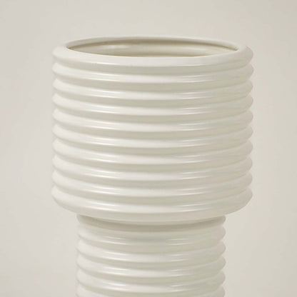 Closeup of white ribbed ceramic vase showing glossy finish and smooth lines ideal for contemporary home decoration.
