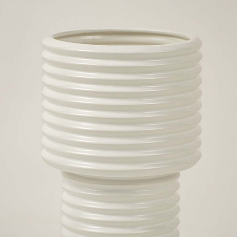 Closeup of white ribbed ceramic vase showing glossy finish and smooth lines ideal for contemporary home decoration.