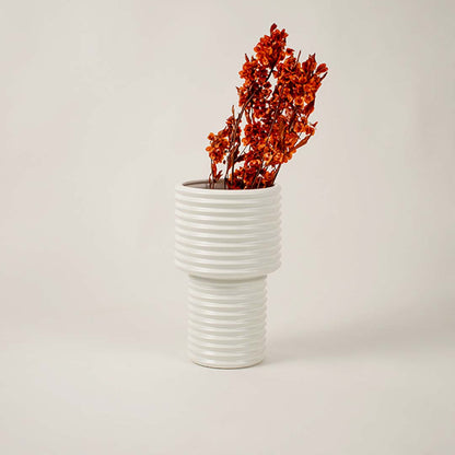 Elegant ribbed white ceramic vase styled beside neutral decor pieces enhances minimalist living room aesthetic.