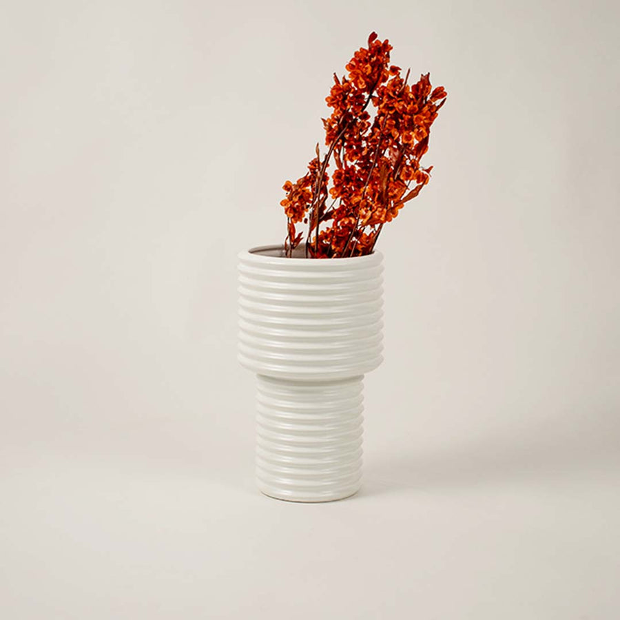 Elegant ribbed white ceramic vase styled beside neutral decor pieces enhances minimalist living room aesthetic.