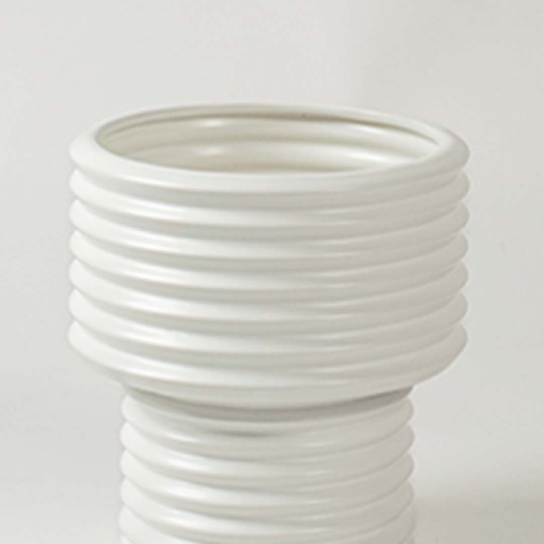 Closeup of white ribbed ceramic vase showing its smooth glossy finish and textured detailing ideal for modern home styling.