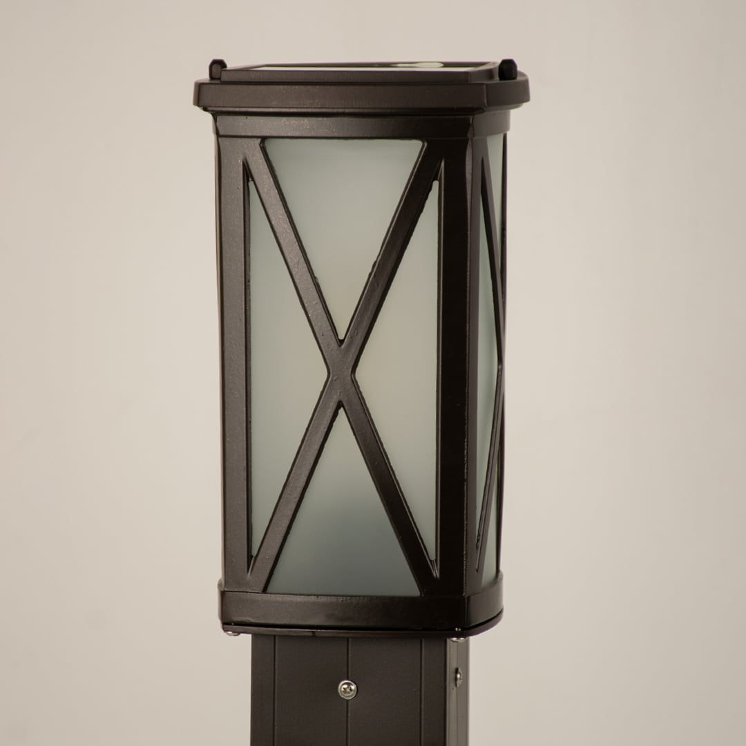 Closeup of black outdoor bollard light with cross metal detailing for modern exterior decor styling.