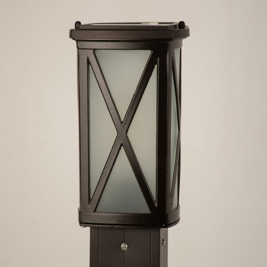 Closeup of black outdoor bollard light with cross metal detailing for modern exterior decor styling.