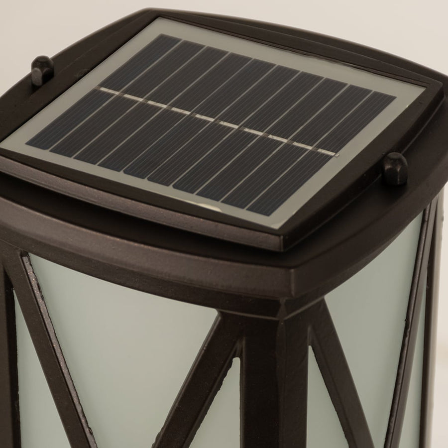 Closeup of black solar outdoor bollard light with top solar panel for smart exterior decor styling.