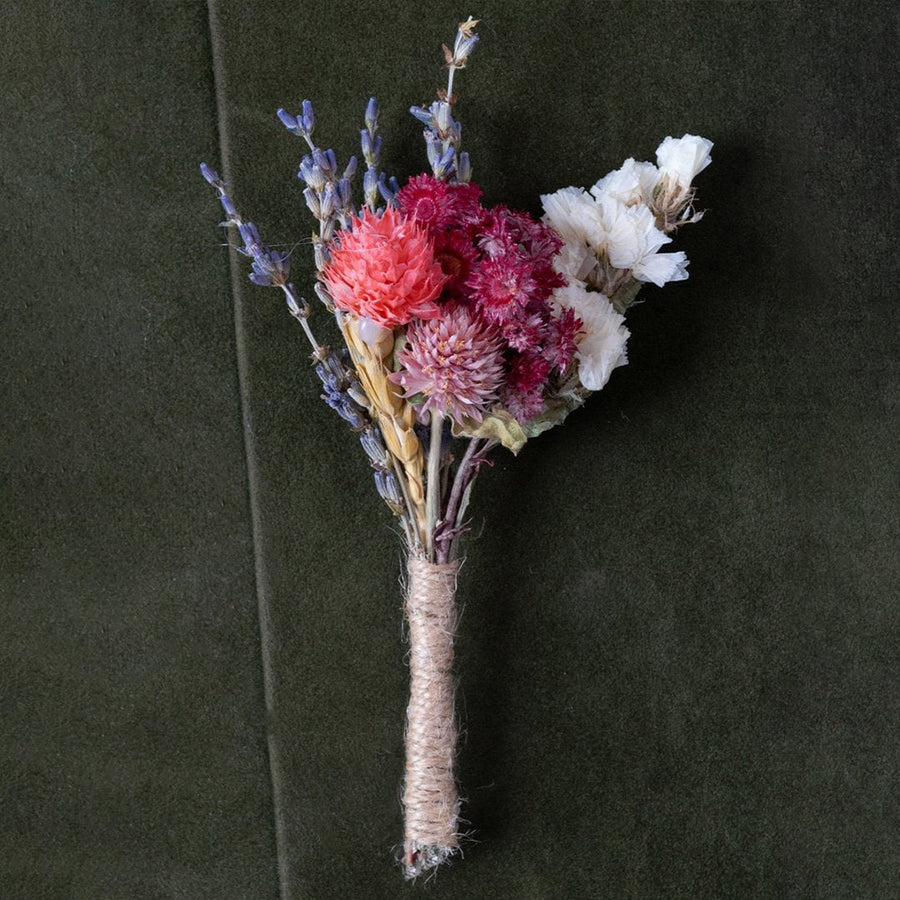 Closeup of dried flower bouquet with pink red purple and white preserved blooms wrapped in jute creating a rustic artificial flower arrangement.