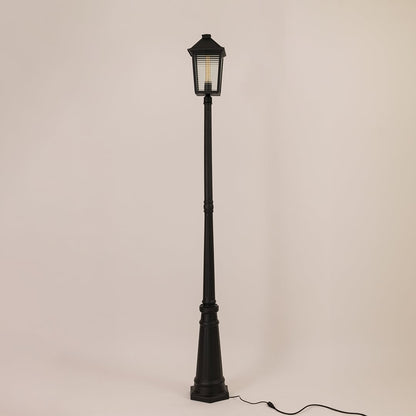 Classic black metal outdoor post light with lantern style head and tall decorative pole switched off on white backdrop.