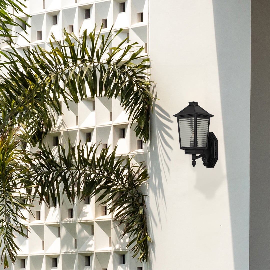 Classic black outdoor wall sconce with ribbed glass lantern and curved bracket mounted creating vintage porch lighting ambiance.