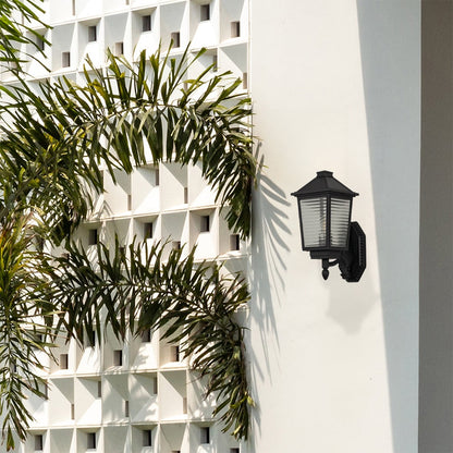 Classic black outdoor wall sconce with ribbed glass lantern and curved bracket mounted creating vintage porch lighting ambiance.