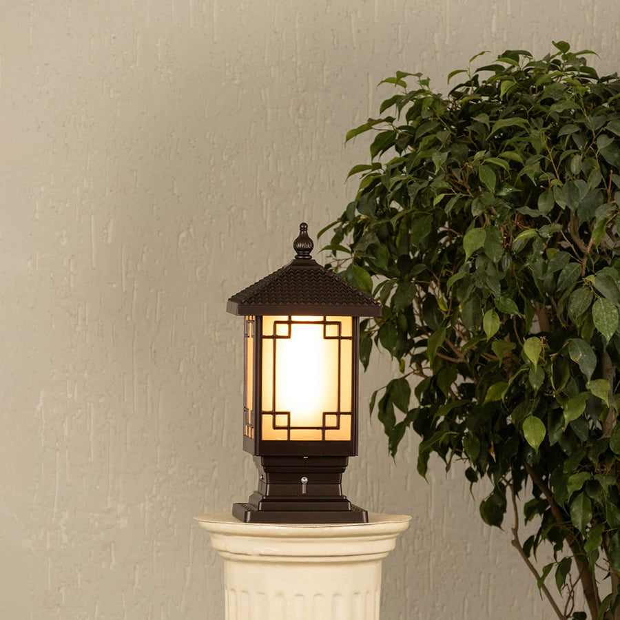 Black metal outdoor post lantern Light On mounted on a stone pillar Traditional garden gate lighting Main Lifestyle image at night.