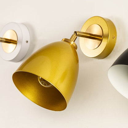 Gold wall light with a sleek metal shade mounted on a round base giving a modern warm focused glow suitable for hallways bedrooms or living spaces.