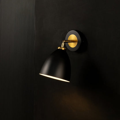 A black metal wall light glowing warmly on a dark ribbed background creating focused illumination and adding stylish modern sconce décor to the interior space.