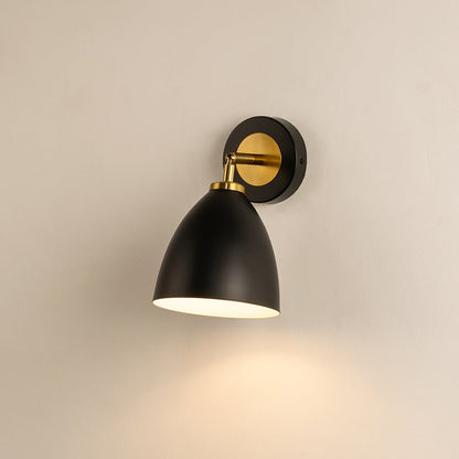 A modern black metal wall light glowing softly against a beige wall creating warm illumination and stylish contemporary sconce décor for modern interiors.