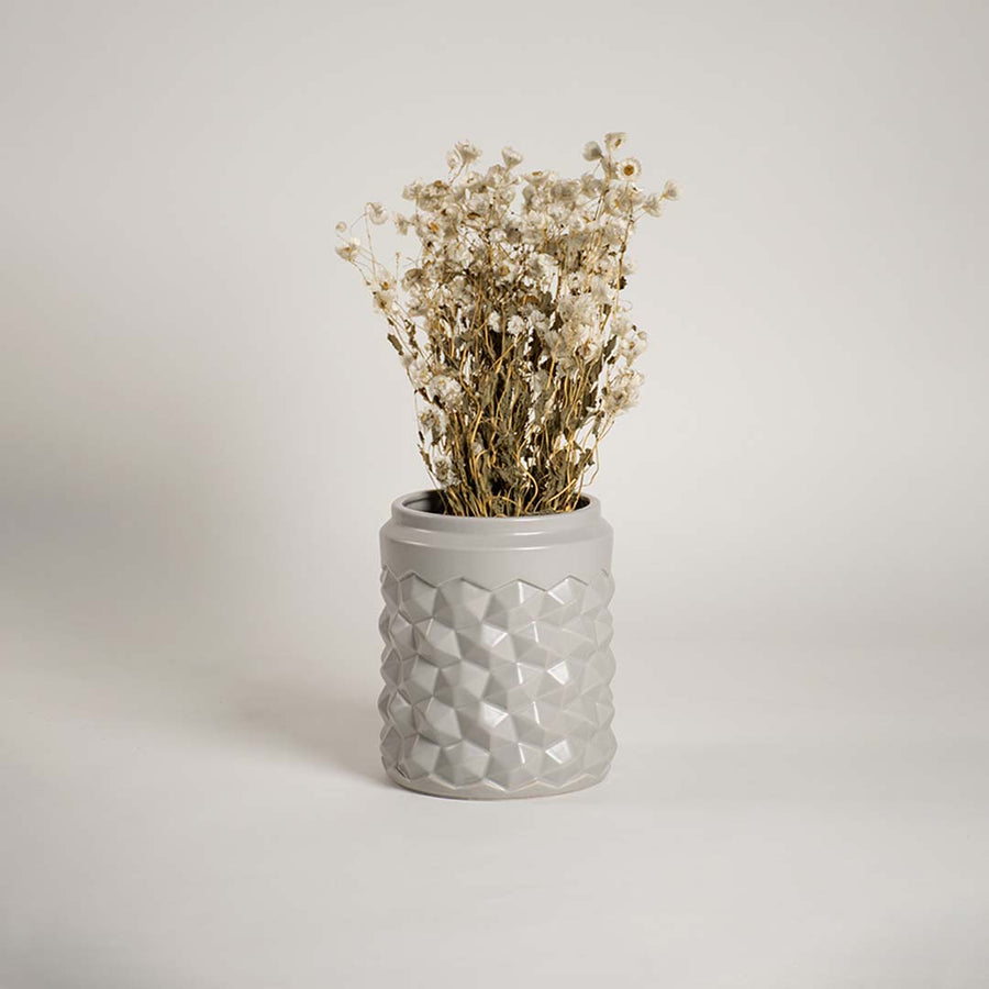 Modern grey ceramic vase with geometric texture displayed in a lifestyle setting enhancing the decor with a subtle contemporary touch.