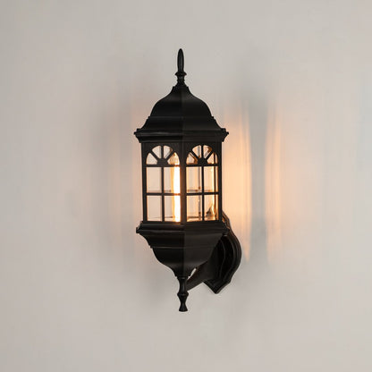Black metal outdoor wall light on white background with an arched paneled glass shade for vintage patio decor.