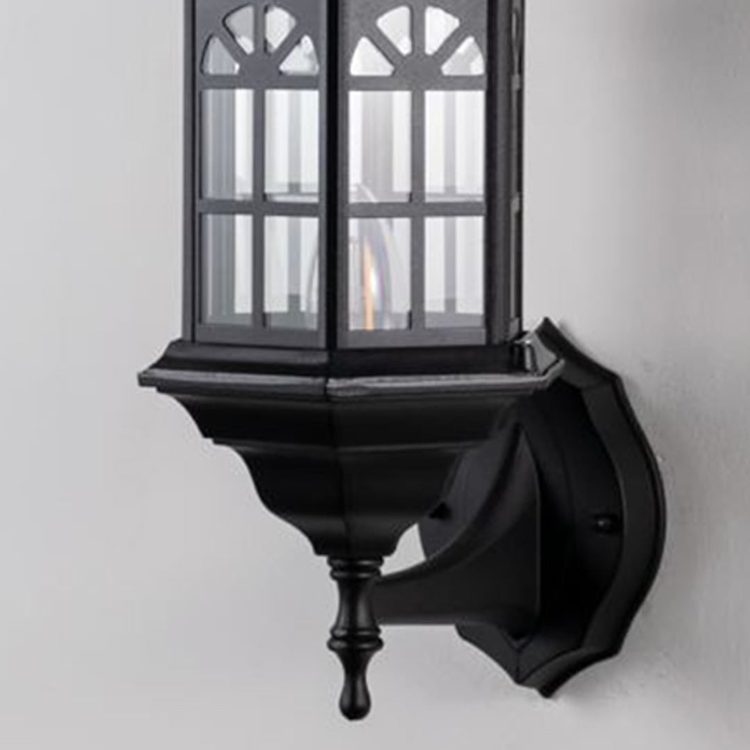 Detailed closeup of traditional outdoor wall lantern showing black metal housing glass panels and curved arm craftsmanship.