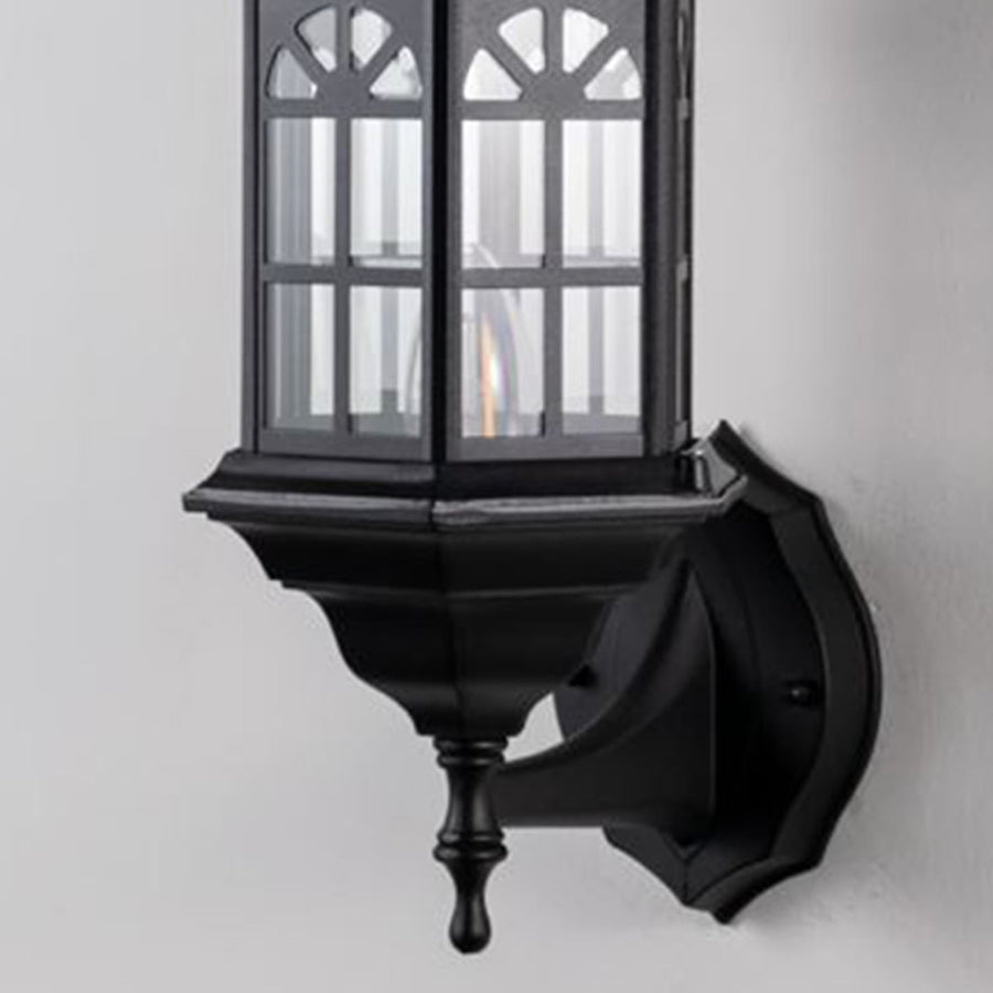 Detailed closeup of traditional outdoor wall lantern showing black metal housing glass panels and curved arm craftsmanship.