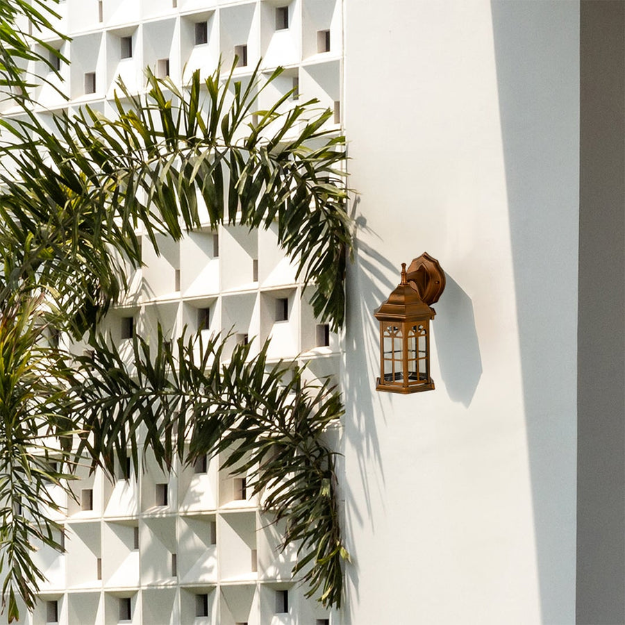 Bronze outdoor lantern with the light off mounted on a bright exterior wall showcasing its classic arched window style glass and elegant vintage lantern design.