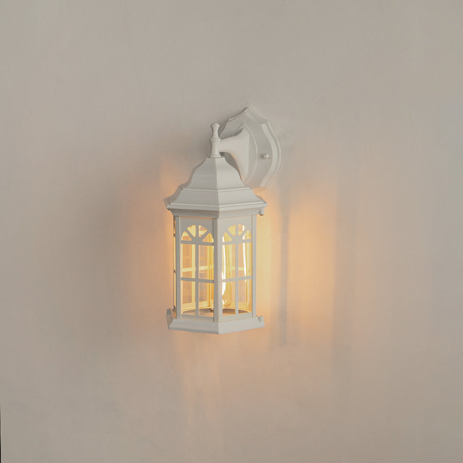 White aluminum outdoor wall lantern on white background with an arched paneled glass shade for vintage porch decor.