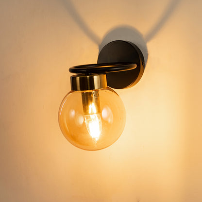 Closeup of amber glass and black metal wall light with warm glow for premium modern decor styling spaces.
