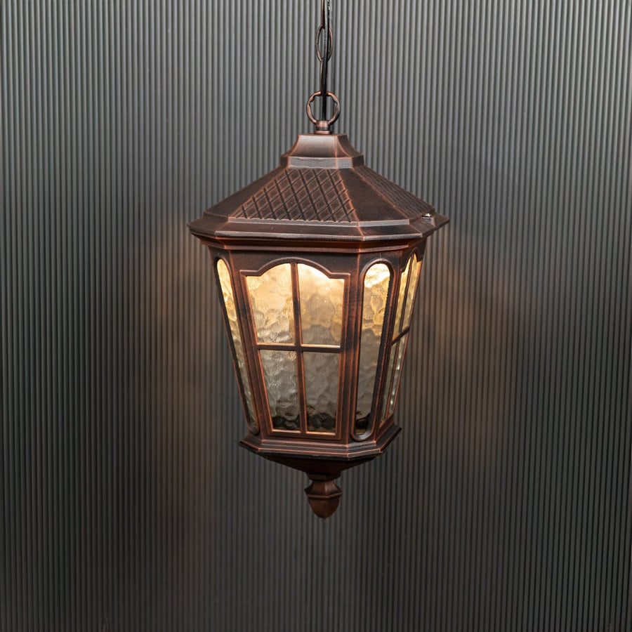 Outdoor hanging lantern glowing warmly against a black background highlights its detailed design.