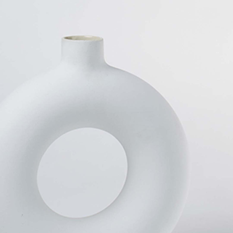 Closeup of large white ceramic donut vase showing smooth glossy surface premium ceramic material and modern decorative form for interior styling.