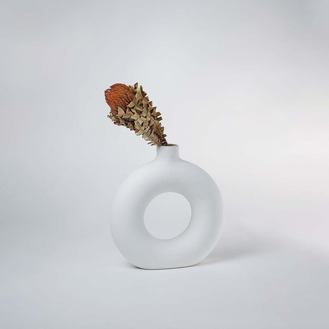 White ceramic donut vase displayed in a clean minimal setting highlighting its sculptural circular form and smooth matte texture ideal for modern home styling.