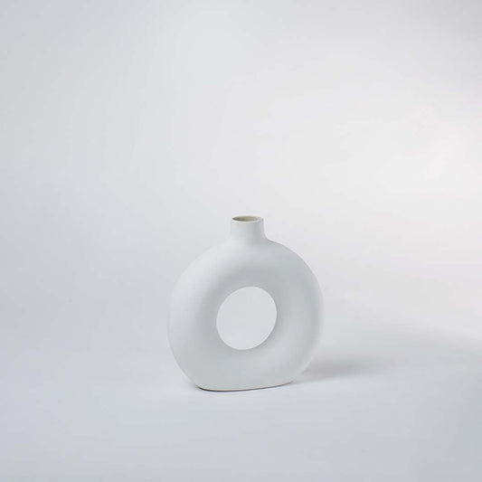 Minimalist round white ceramic vase with hollow center on a plain background – modern home decor vase.