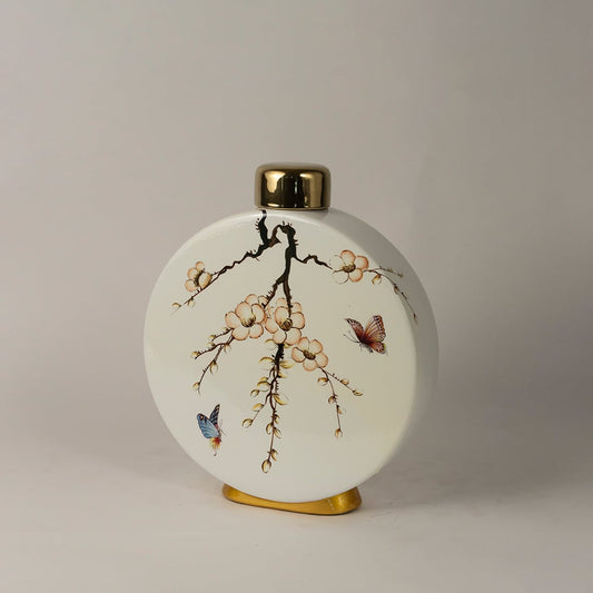 Side angle view of round ceramic jar showing gold top and blooming floral design with butterfly detailing.