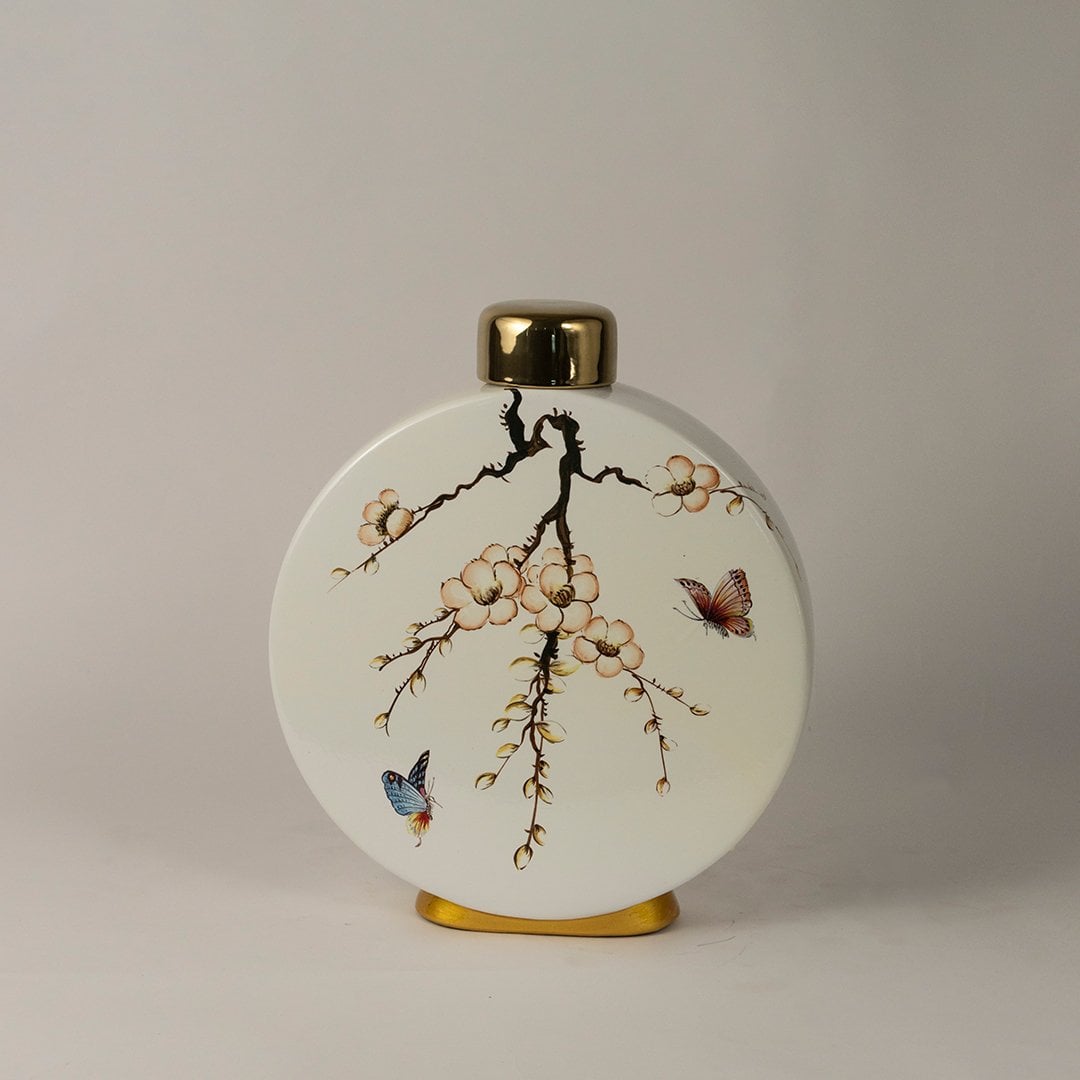 Round ceramic jar against white background emphasizing glossy finish and gold-topped lid.