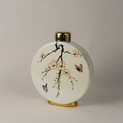 Side angle view of round ceramic jar showing elegant floral branches and butterfly painting with gold detailing.