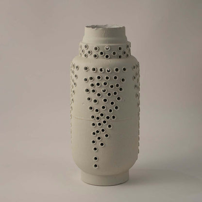 Tall white ceramic vase with modern perforated hole design styled for elegant living room and contemporary home decoration.