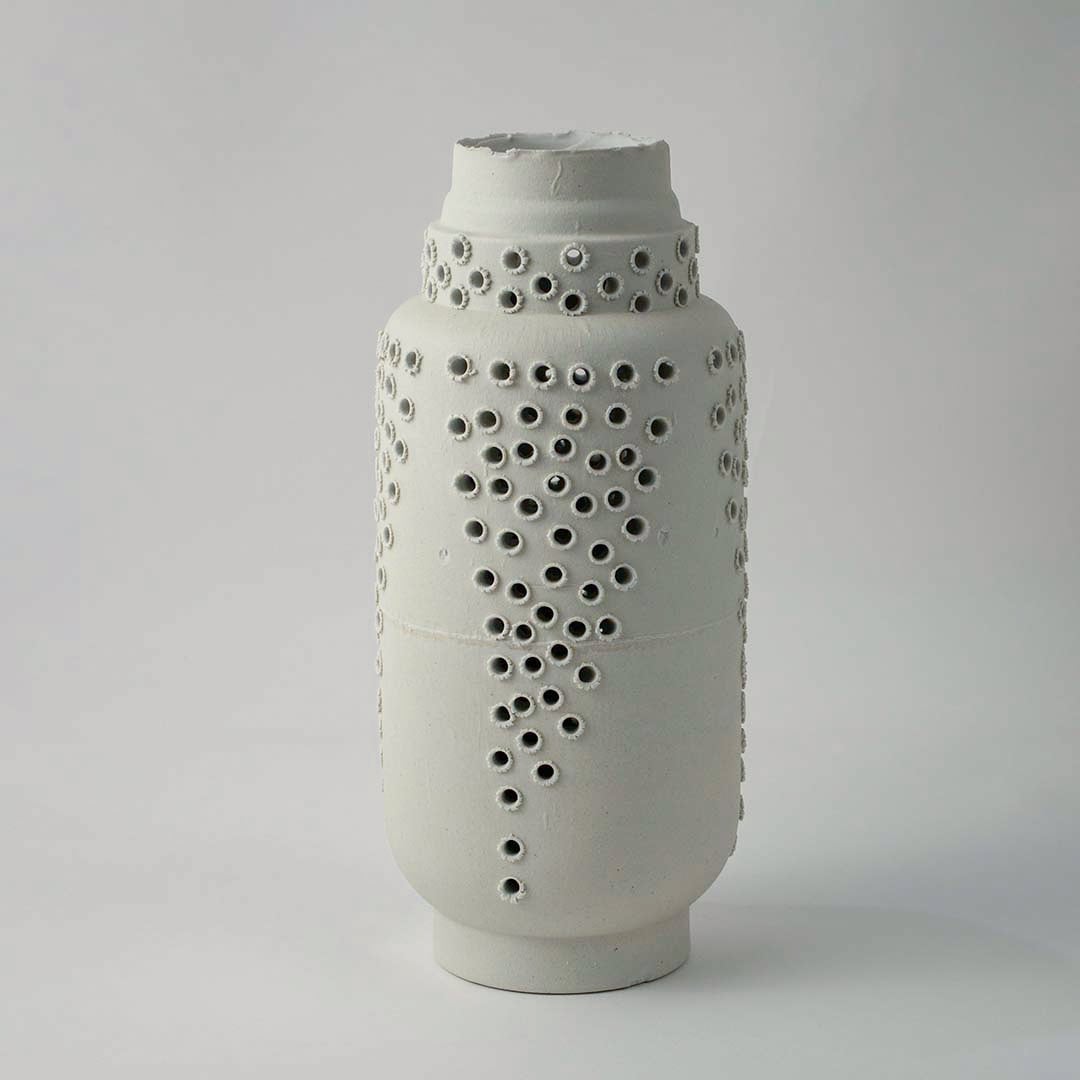Tall white ceramic vase with modern perforated hole design styled for elegant living room and contemporary home decoration.