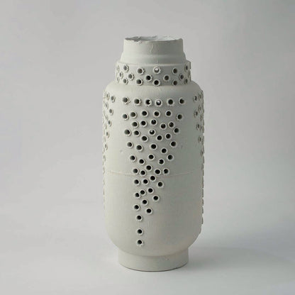 Tall white ceramic vase with modern perforated hole design styled for elegant living room and contemporary home decoration.
