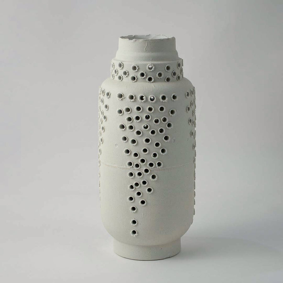 Tall white ceramic vase with modern perforated hole design styled for elegant living room and contemporary home decoration.