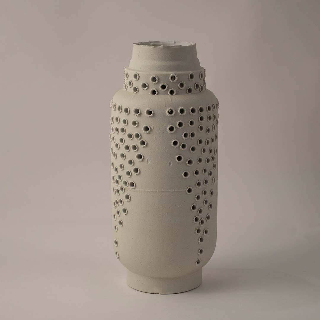 Side angle view of tall white ceramic vase with perforated textured surface perfect for stylish modern shelf and table styling.