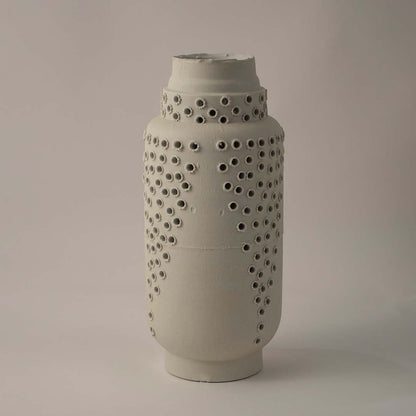 Side angle view of tall white ceramic vase with perforated textured surface perfect for stylish modern shelf and table styling.